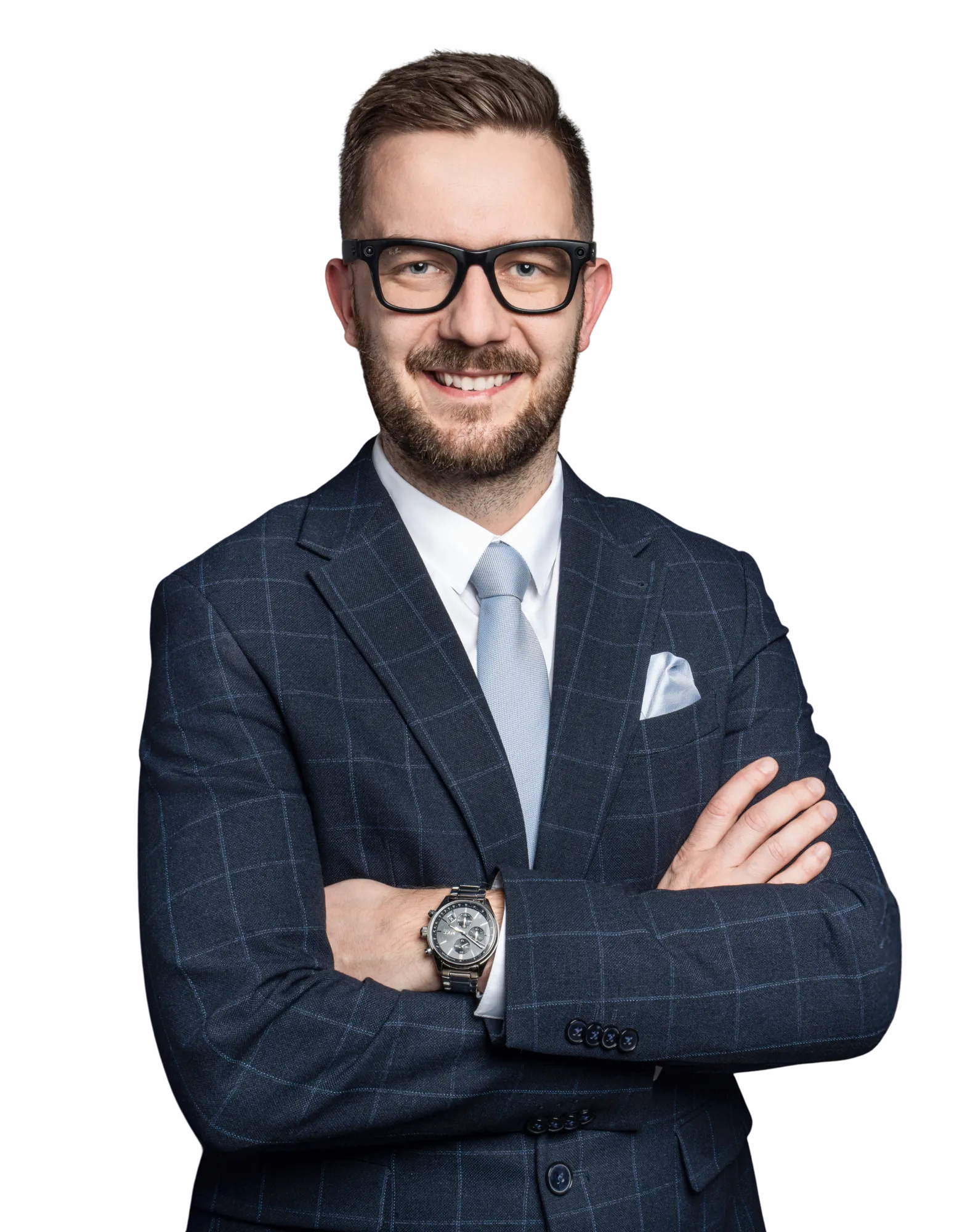 Jan Johny Vašourek, usměvavý muž s plnovousem a brýlemi v modrém kostkovaném obleku se založenýma rukama.